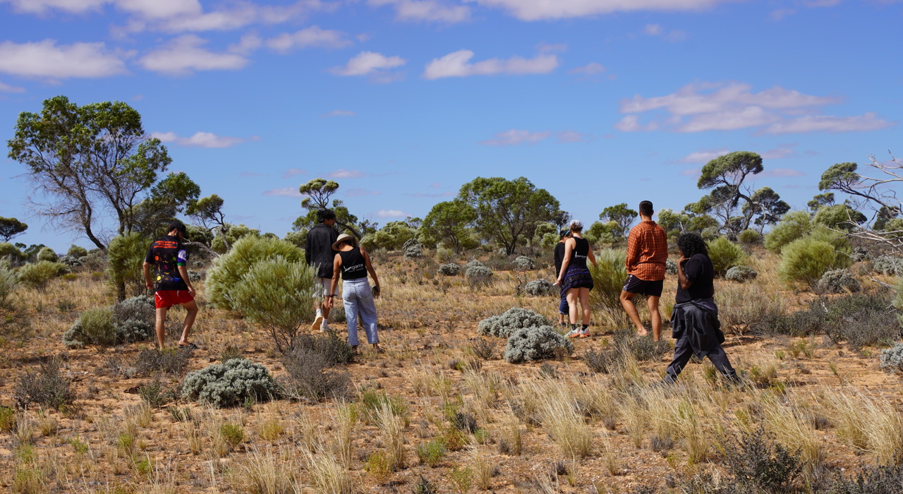 Artistic Director Frances Rings and dancers walking on Country